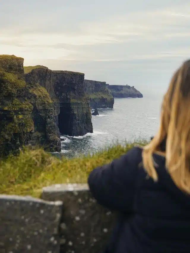 A woman looks out over the sea at the famed Cliffs of Moher, which run for 8.5 craggy miles