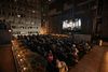 People sit in deckchairs on a roof watching a film projected on a screen at Rooftop Cinema Club in Midtown New York City
