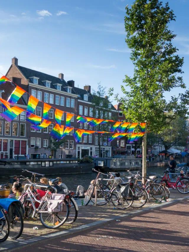 Rainbow flags strung between trees on a treelined canal in Amsterdam