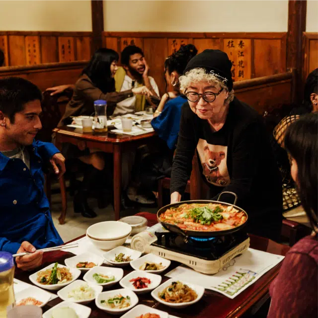 Odri Chang brings a dish to diners at a table at Chunju Han Il Kwan