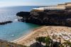 A hidden golden cove where turquoise waters meet dramatic volcanic cliffs