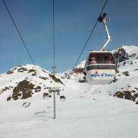 A cable car climbs up snow-covered Alpe d'Huez on a clear day in France