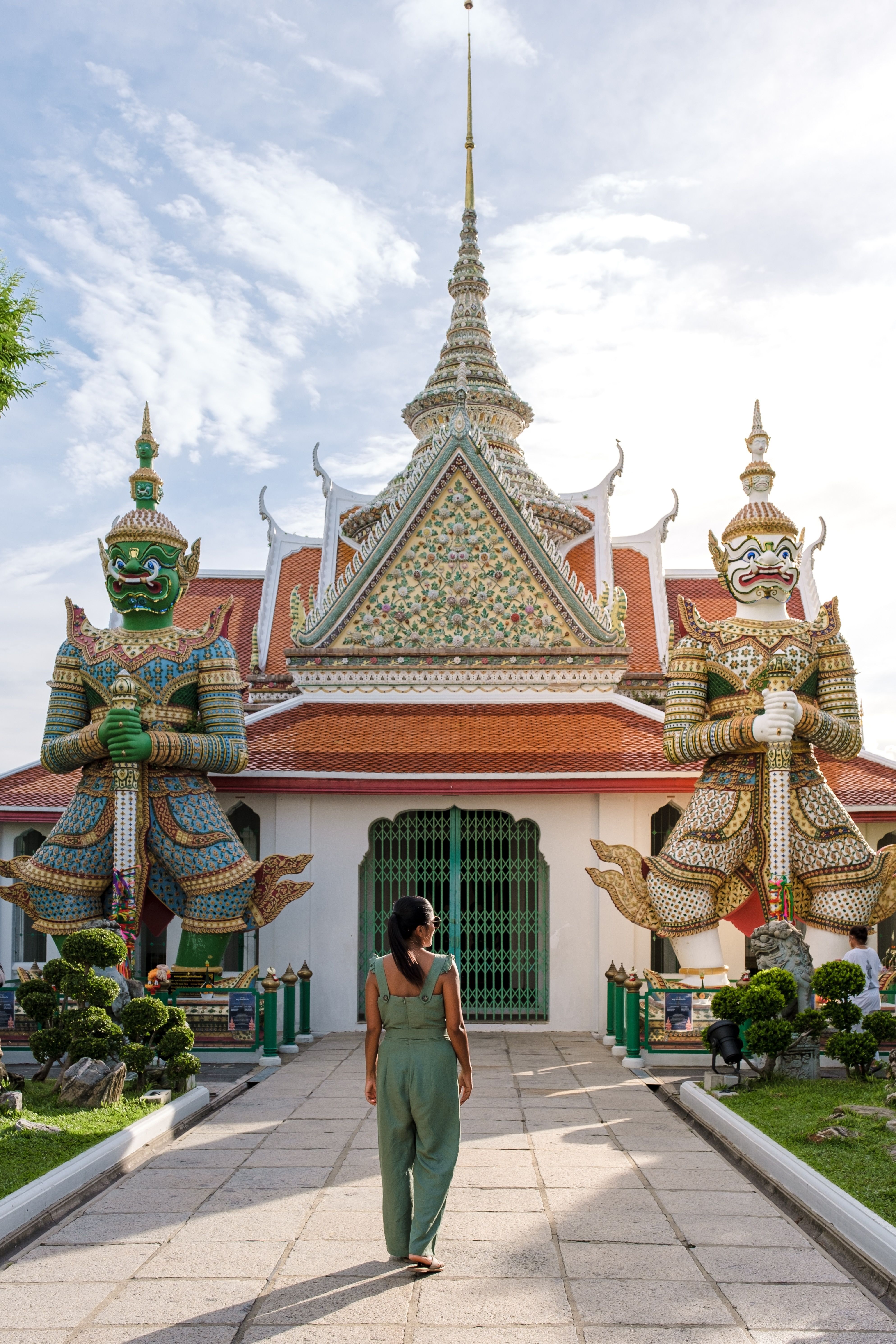 A woman stands outside Wat Arun Ratchawararam Ratchawaramahawihan Buddhist temple in Bangkok, Thailand