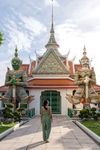 A woman stands outside Wat Arun Ratchawararam Ratchawaramahawihan Buddhist temple in Bangkok, Thailand