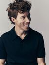 Snowboarder Shaun White smiles wearing a black polo shirt