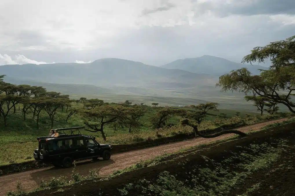 A safari jeep drives through verdant Ngorongoro Crater, Tanzania