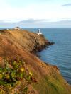 The steep hills along the Howth coast with a lighthouse at the tip in County Dublin, Ireland