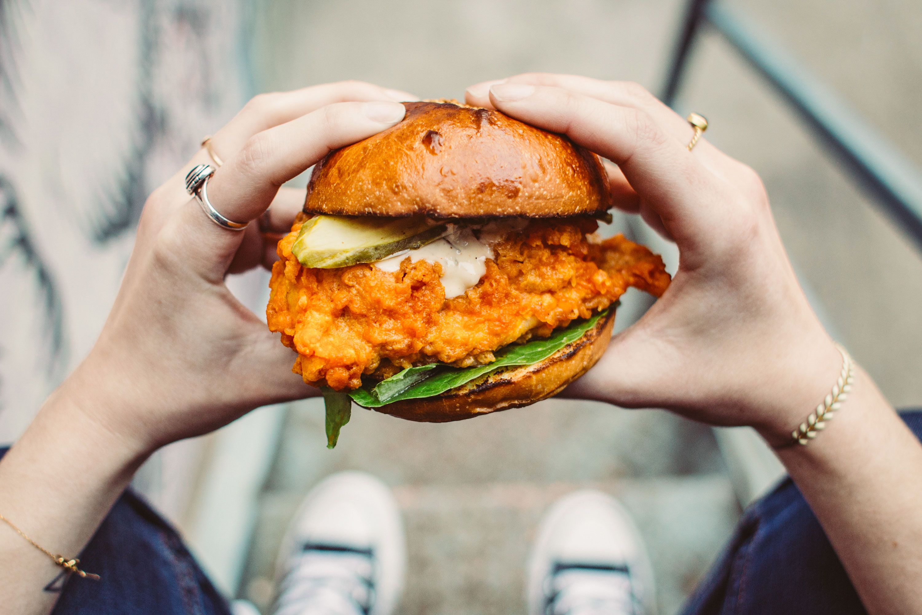 Perspective from the consumer of a fried chicken sandwich in their hands.