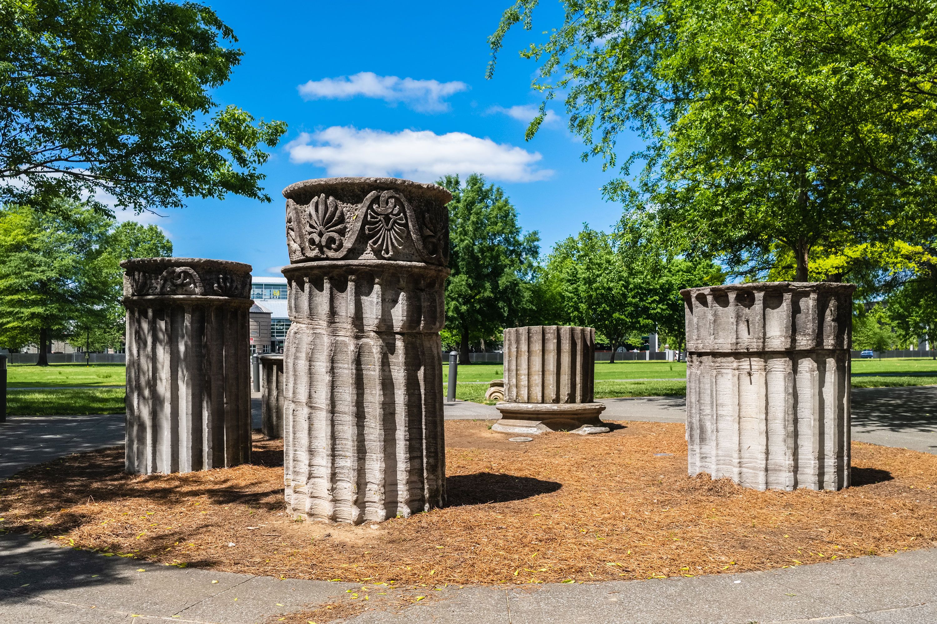 Outdoor park with portions of columns in central woodchip area.