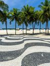 The wave-patterned floor tiles and palm trees along the edge of Copacabana Beach in Rio de Janeiro
