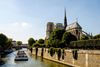 A boat cruises along the river Seine next to Notre-Dame cathedral in Paris, France