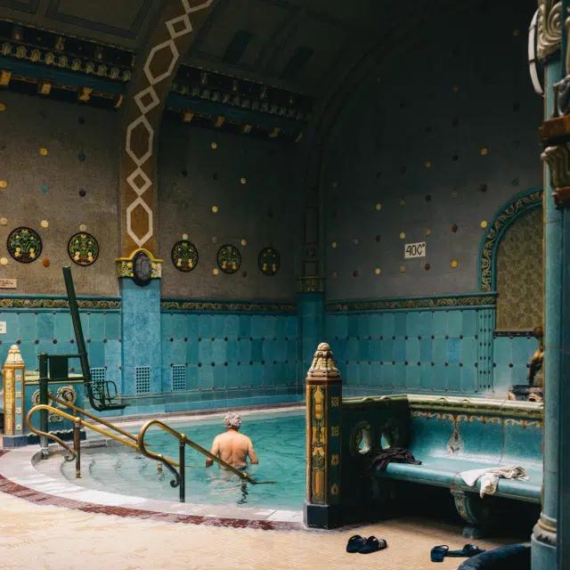 A man wades into the water at the ornately tiled, art nouveau-style Gellért Thermal Bath in Budapest, Hungary