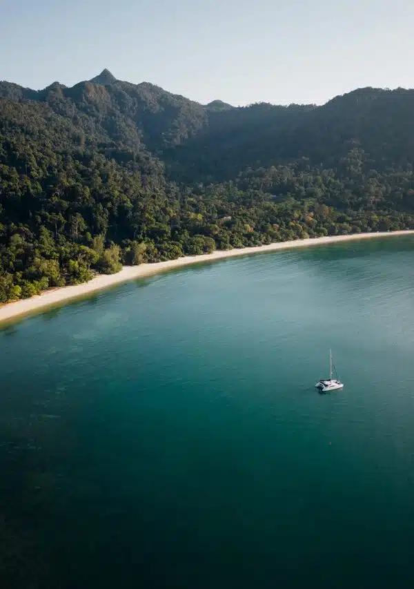 A boat anchored in the tree-lined Datai bay, Langkawi, Malaysia