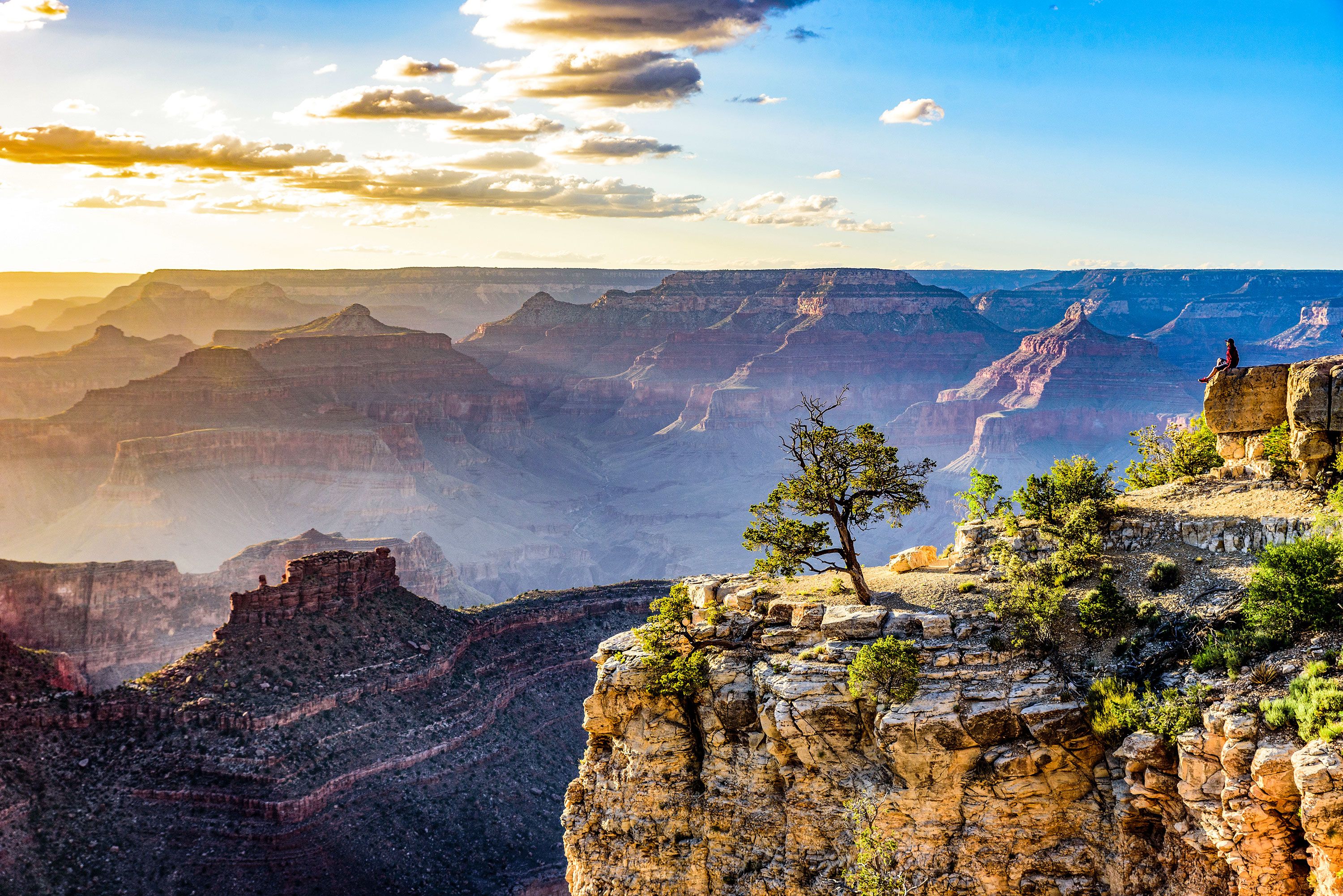 Someone in the middle distance views huge and expansive series of canyons on a hazy day.