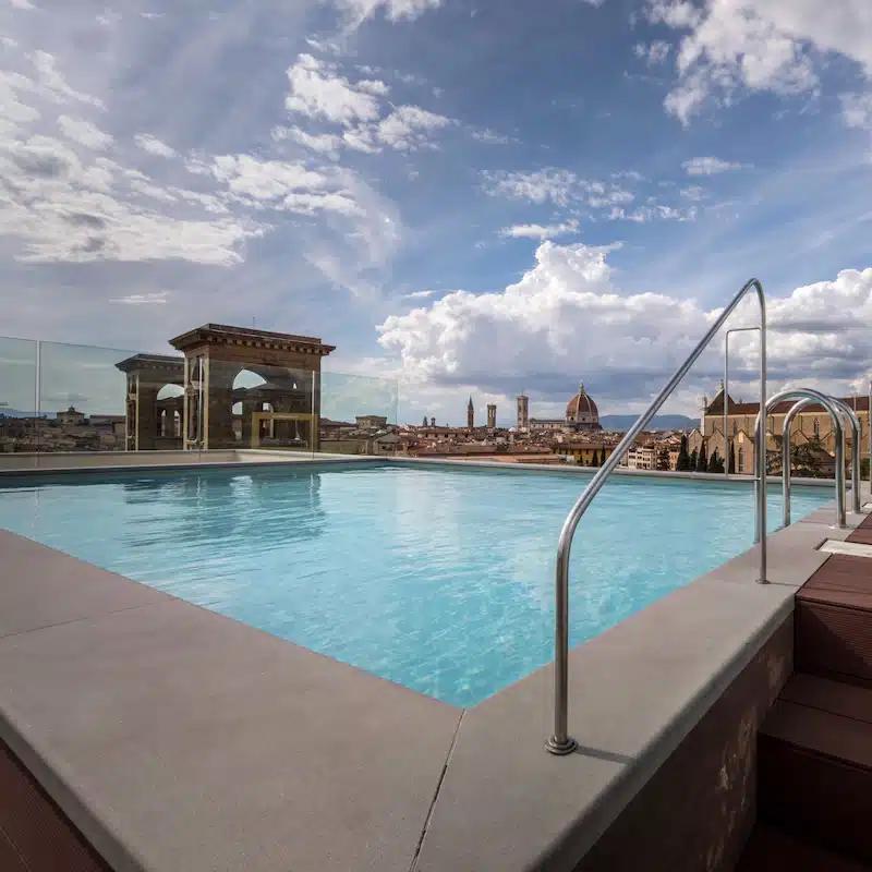 The rooftop pool at Plaza Hotel Lucchesi on a bright, partly cloudy day in Florence, Italy