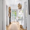 A light filled hallway with lots of straw hats on hooks