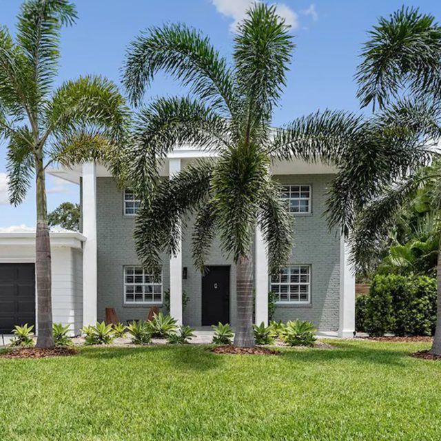 Palm trees in front of a grand Vrbo with tall pillars in Cocoa Beach, Florida 