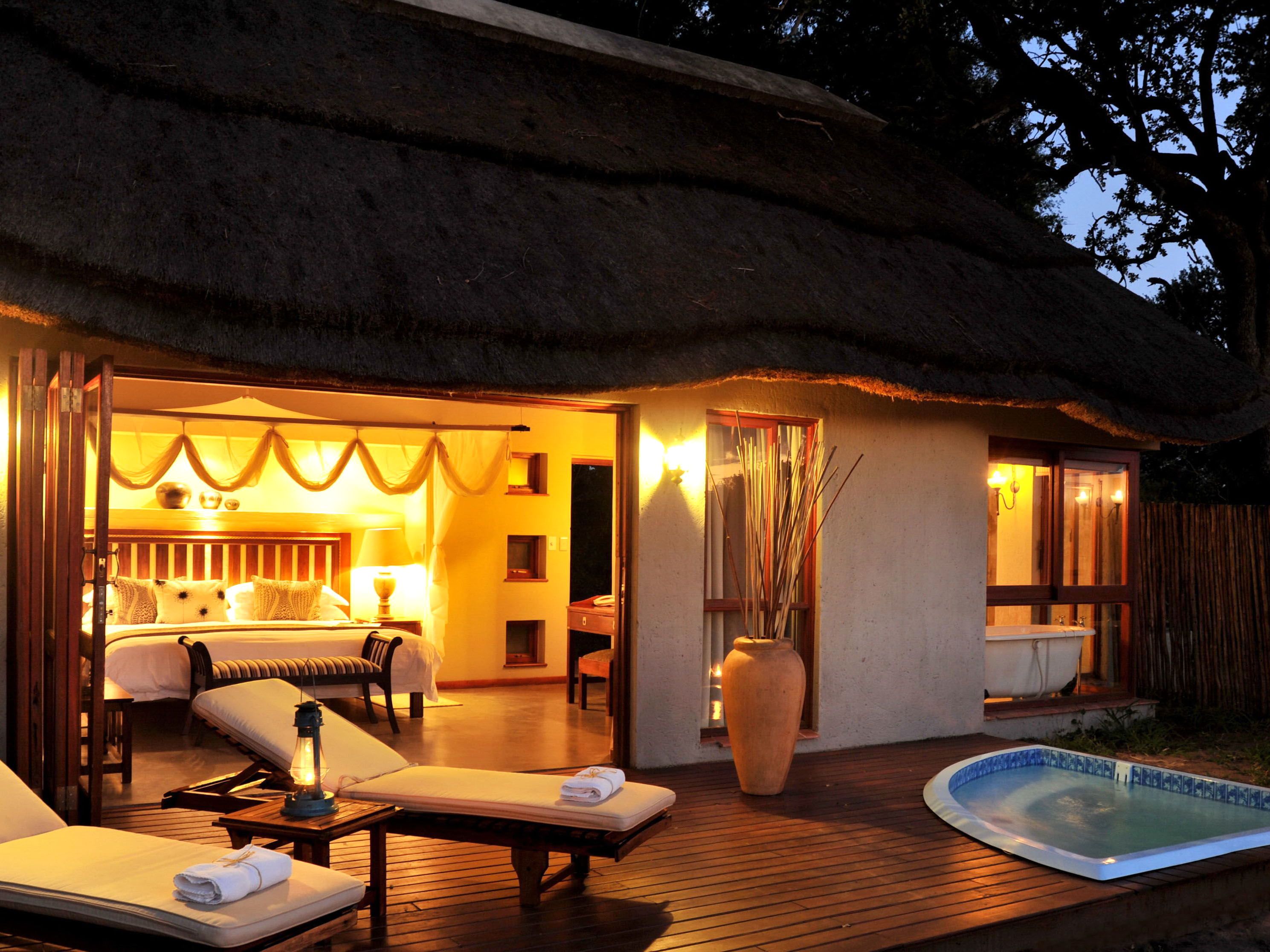 Nighttime view of outdoor patio with two lounge chairs outside room accomadations with a hot tub.
