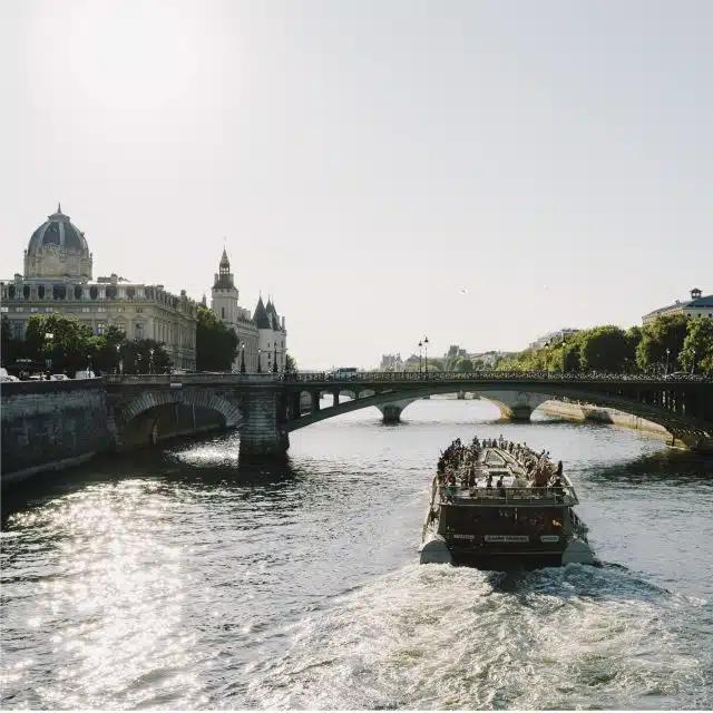A boat plies the waters of the Seine on a sunny day in Paris