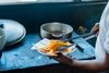A chef tongs slices of tropical fruit into a pan in a restaurant kitchen in Panama City