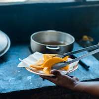 A chef tongs slices of tropical fruit into a pan in a restaurant kitchen in Panama City