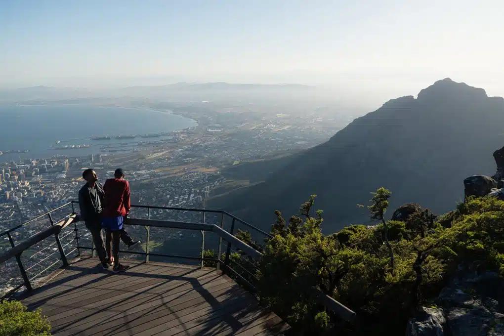 Two people stand on a viewing platform on Table Mountain, overlooking the city and bay of Cape Town, South Africa