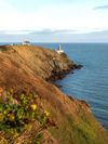 The steep hills along the Howth coast with a lighthouse at the tip in County Dublin, Ireland