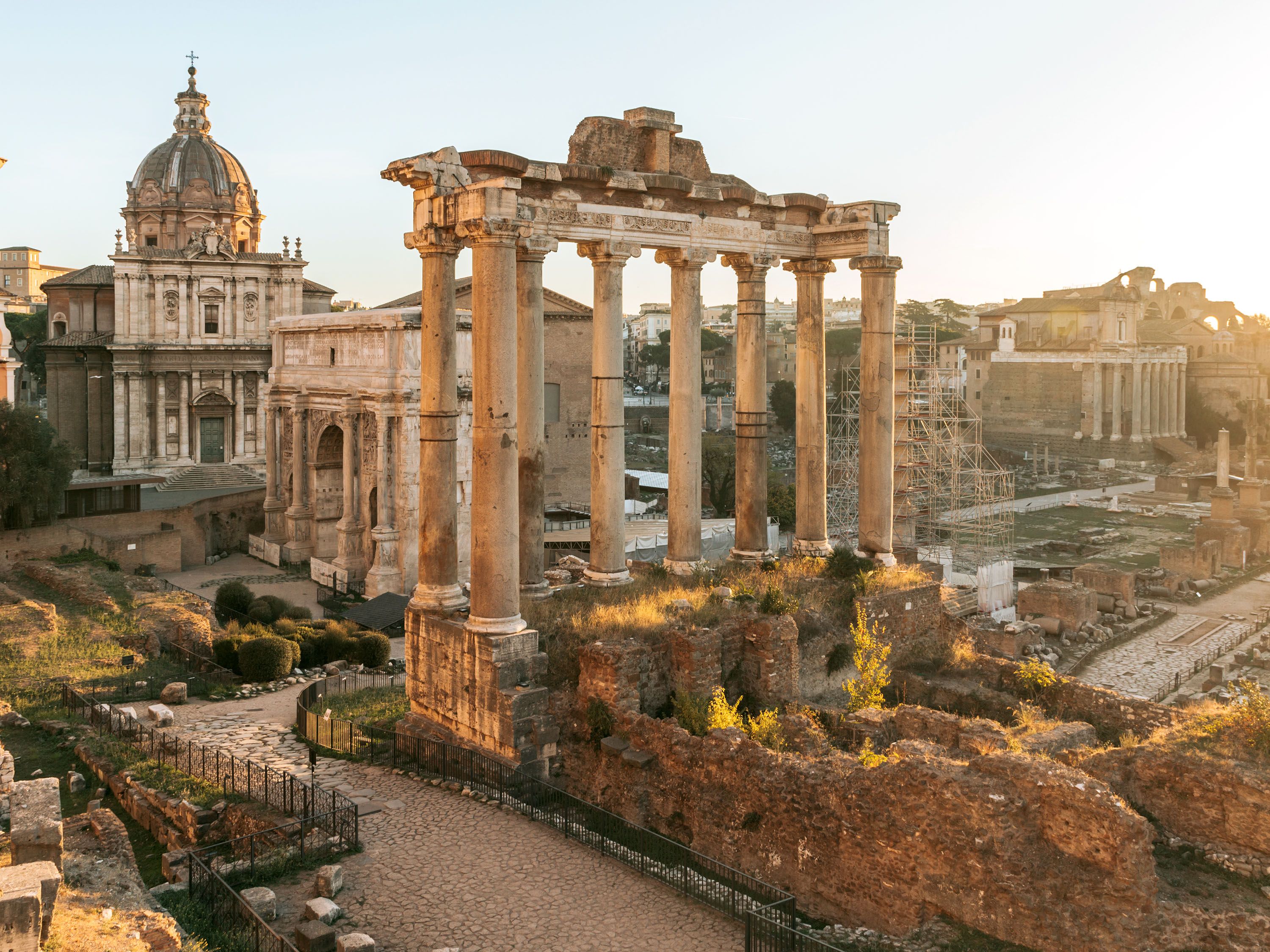 The sun sets on the ancient ruins of the Roman Forum and Palatine Hill.