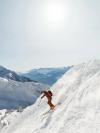 A person skis down a steep backcountry slope on a sunny day in Denver, Colorado