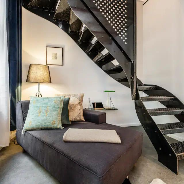 The living area of a townhouse in Berlin’s Prenzlauer Berg neighborhood, with a daybed and curving metal staircase