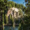 The Grand Canyon of the Yellowstone with a dark green river flowing past green trees and white rocks