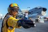 A statue of a pilot pointing his arm and fingers forward with a fighter jet in the background.
