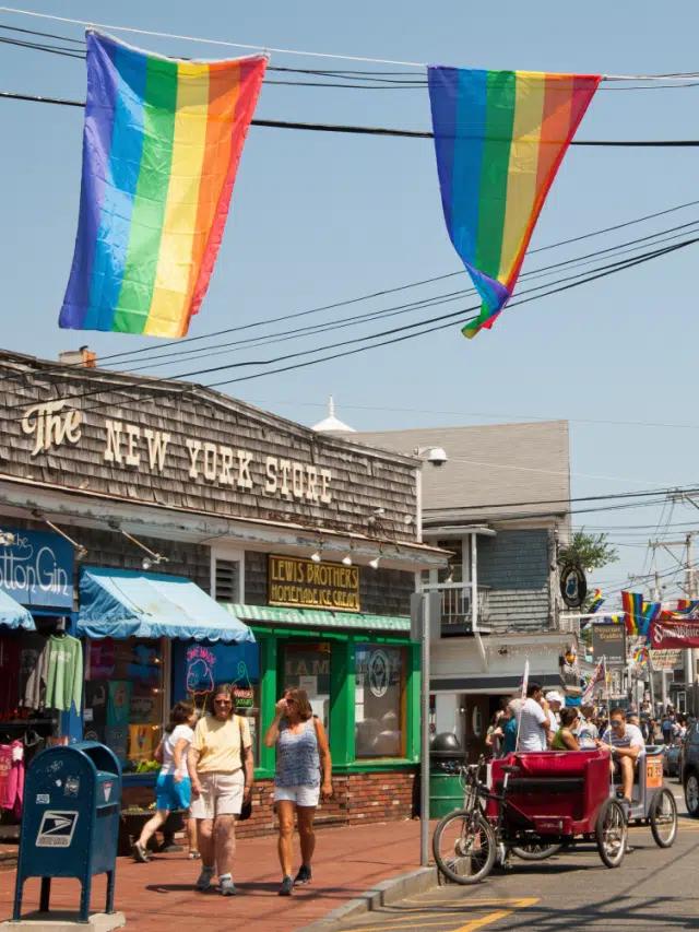 Rainbow flags hang above a street in Provincetown, Massachusetts, with an old-fashioned store behind