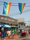 Rainbow flags hang above a street in Provincetown, Massachusetts, with an old-fashioned store behind