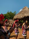 Tribe members in the Emberá village of Parara Purú wearing floral headdresses and brightly colored fabric skirts clap their hands
