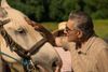 Eugene Levy leans in and strokes a horse's head in France