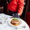 A waiter serves a plate of steak with a martini at The Musso & Frank Grill in Los Angeles, California