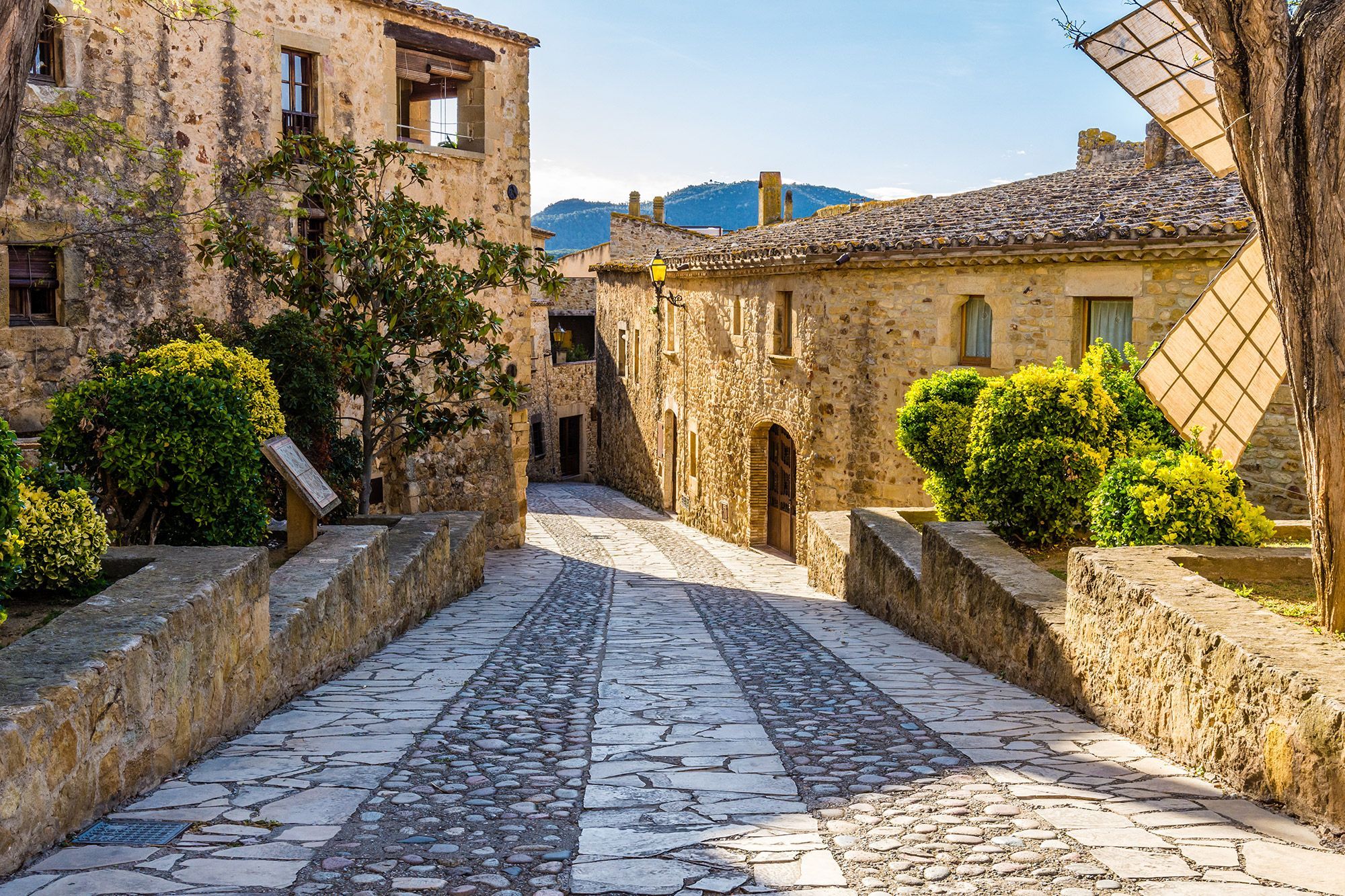 Brick buildings line a cobblestone street in Girona, Spain.