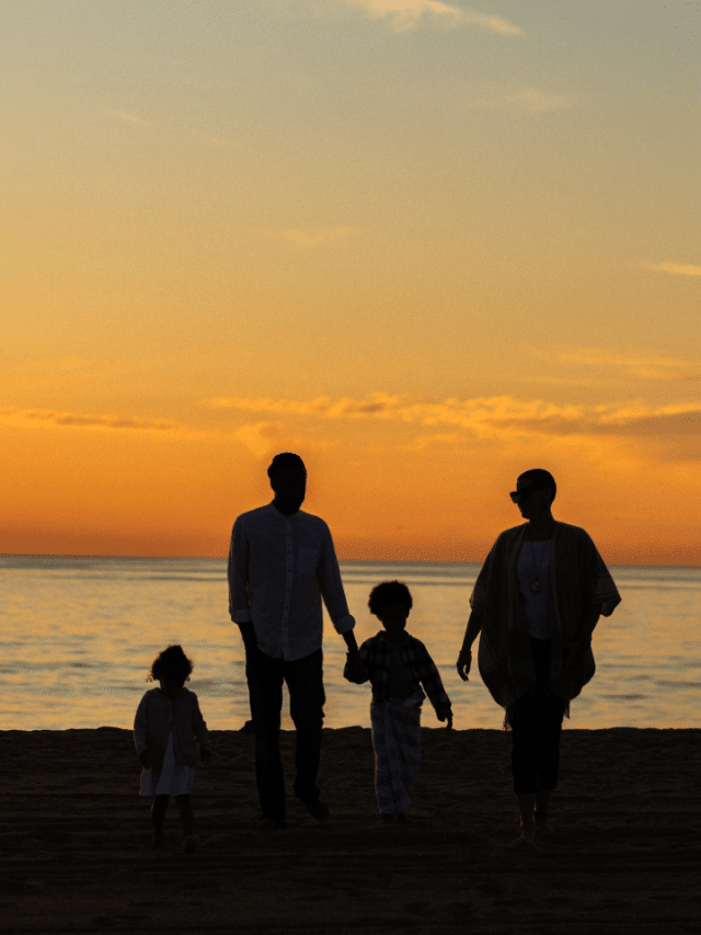 A family silhouetted on a beach at sunset