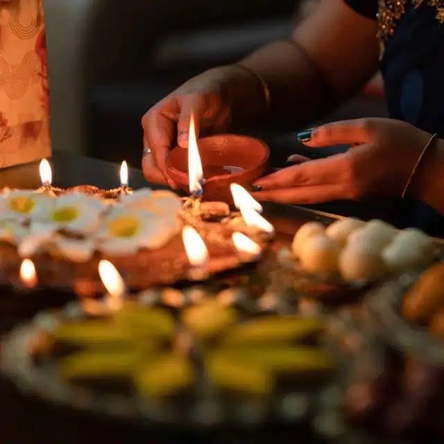 A person lights traditional Diya lamps