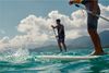 Two standup paddleboarders on blue water, with Hawaiian islands behind them