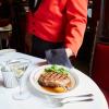 A waiter serves a plate of steak with a martini at The Musso & Frank Grill in Los Angeles, California