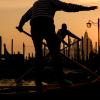 Gondoliers in classic striped shirts paddle their oars in the canal at sunset in Venice, Italy