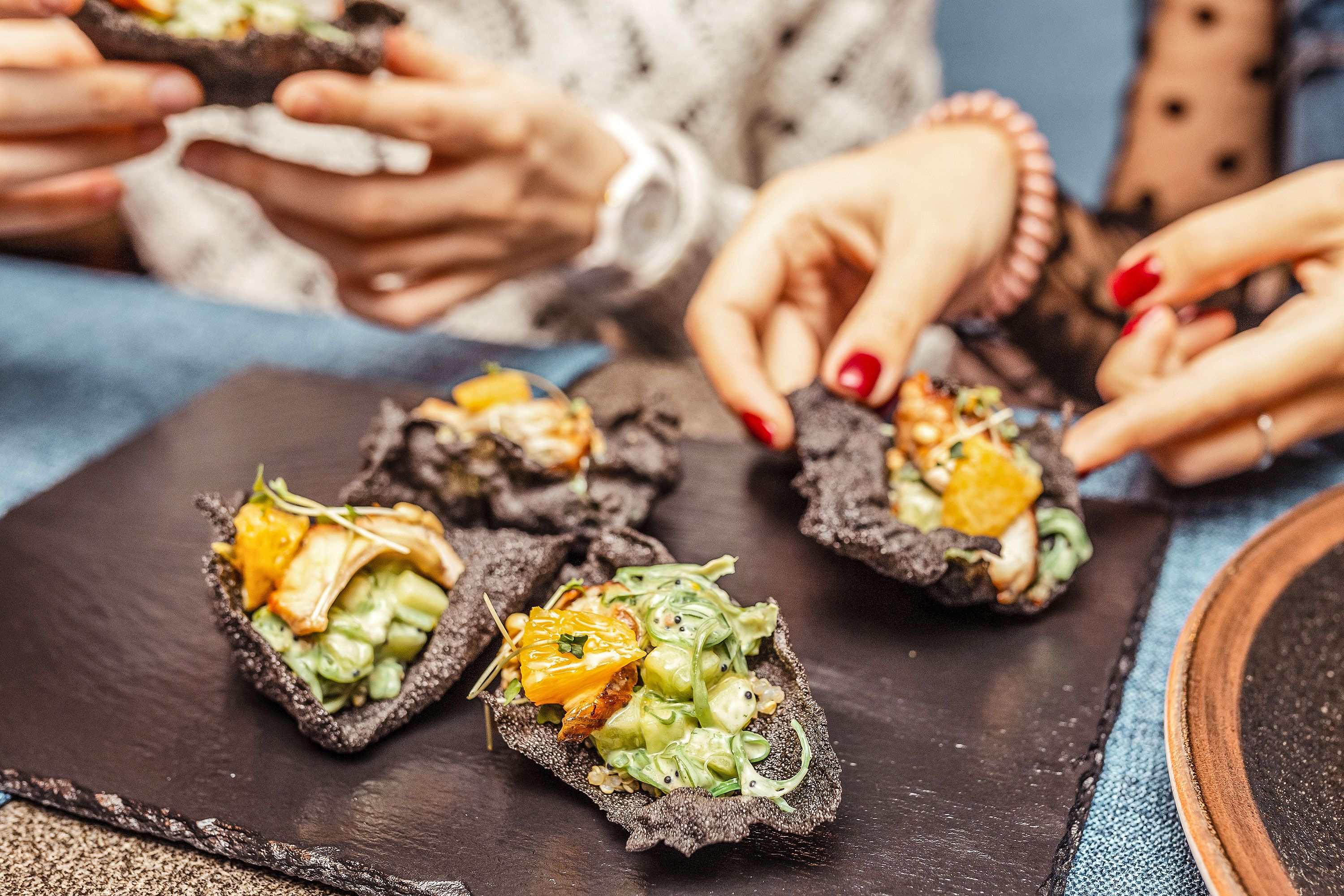 Close-up view of tapas with women's hands handling some of the food.