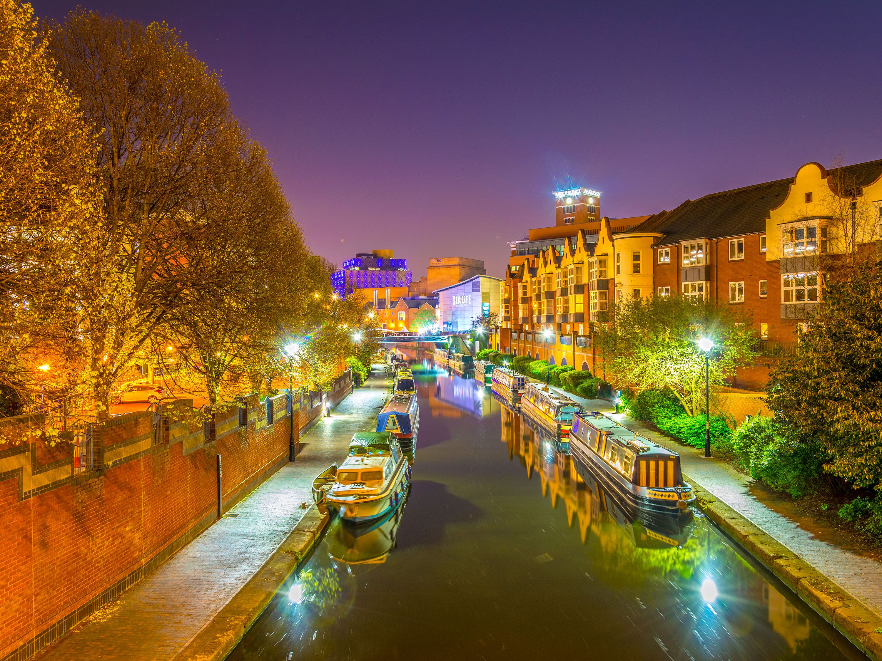 River at night with boats tied up and apartment homes.