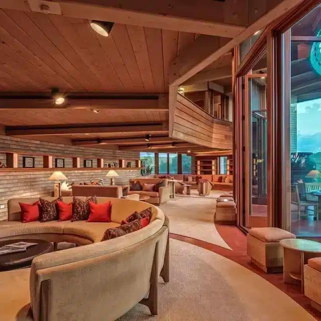 Curved sofas and floor-to-ceiling windows follow Frank Lloyd Wright's distinctive style at a Vrbo in Hawaii
