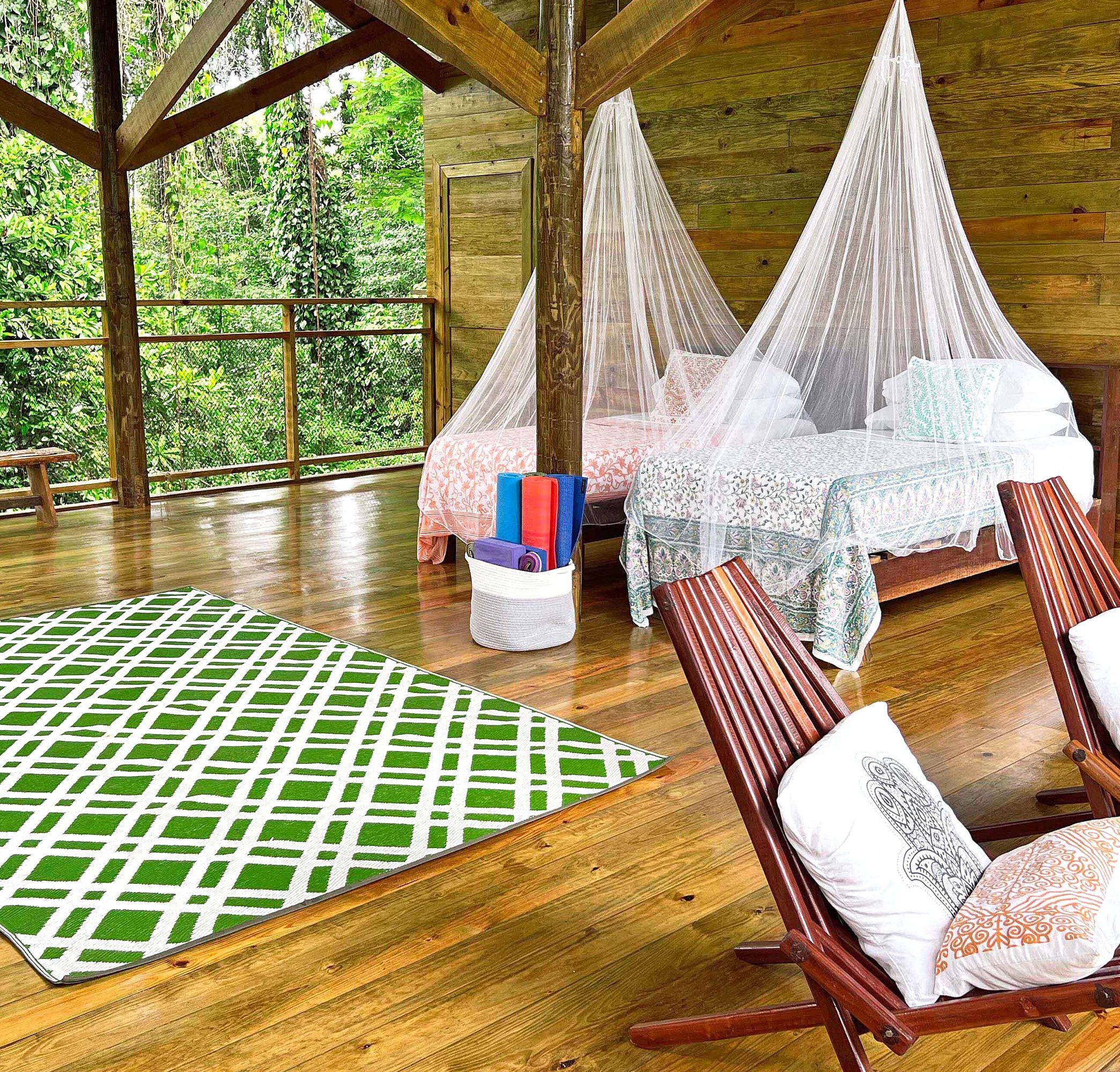 Two wooden chairs sit near two small beds covered in mosquito netting.