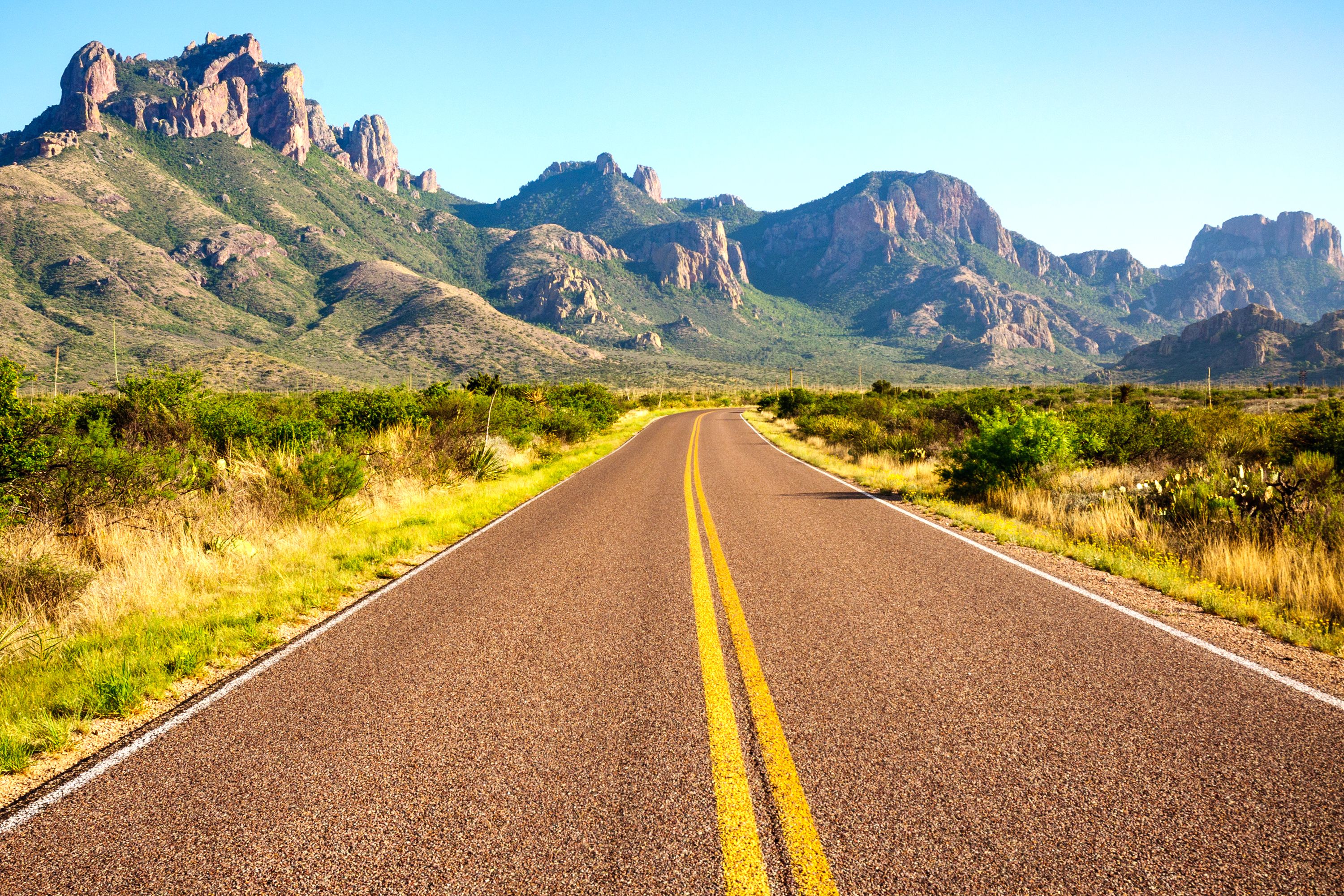 A highway crossing the plains, rocky peaks on the side of the road.