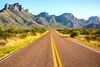 A highway crossing the plains, rocky peaks on the side of the road.
