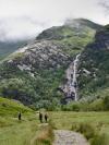 The cinematic Steall Falls in Glen Nevis run down a lush but rocky hillside with a trail in the foreground